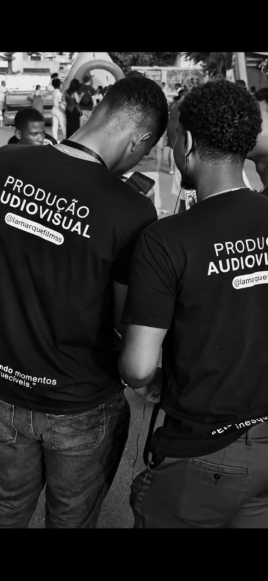 Equipe da Lamarque Films em produção, de costas, com camisas da marca em cobertura de evento